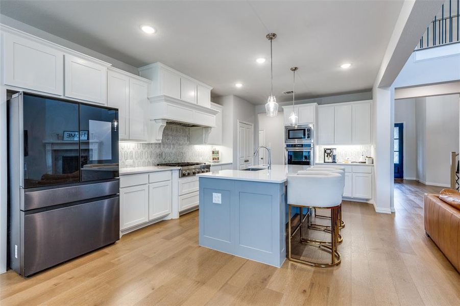 Kitchen featuring white cabinets, sink, hanging light fixtures, an island with sink, and appliances with stainless steel finishes