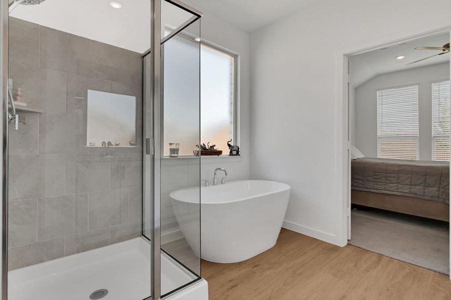 Ensuite bathroom featuring a shower stall, a freestanding tub, wood finished floors, and recessed lighting