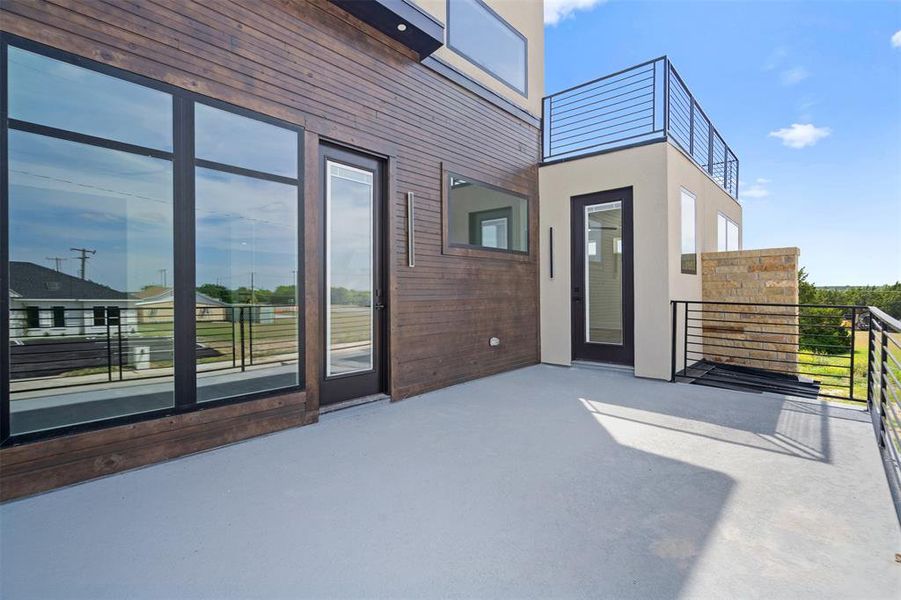 Spacious outdoor deck featuring a light-colored surface, modern black railings, and stone accent wall, providing an inviting exterior area Spacious outdoor deck featuring a light-colored surface, modern black railings, and stone accent wall, providing an inviting exterior area