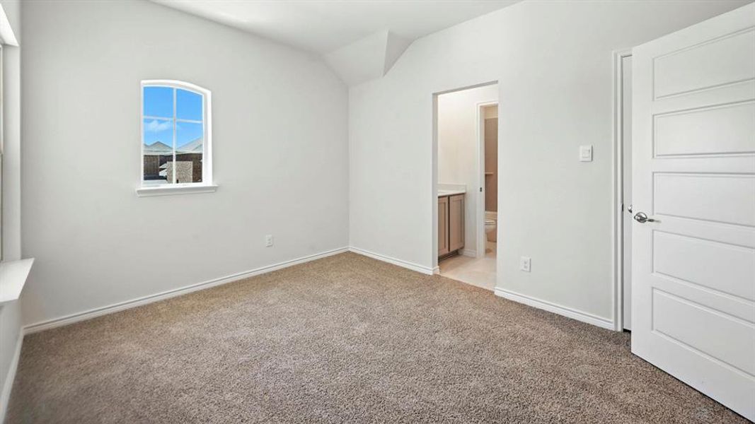 Unfurnished bedroom with vaulted ceiling, light colored carpet, and ensuite bath