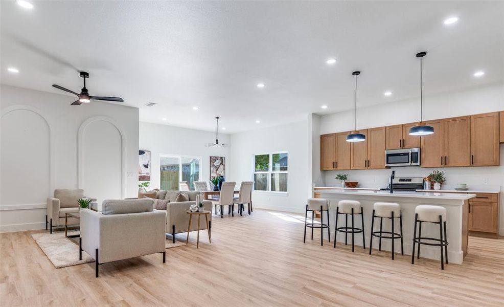 Kitchen with a breakfast bar area, open floor plan, light wood-style flooring, hanging light fixtures, and recessed lighting Kitchen with a breakfast bar area, open floor plan, light wood-style flooring, hanging light fixtures, and recessed lighting
