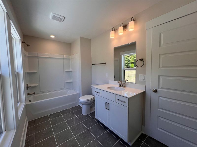 This bright bathroom features a vanity, bathtub, a