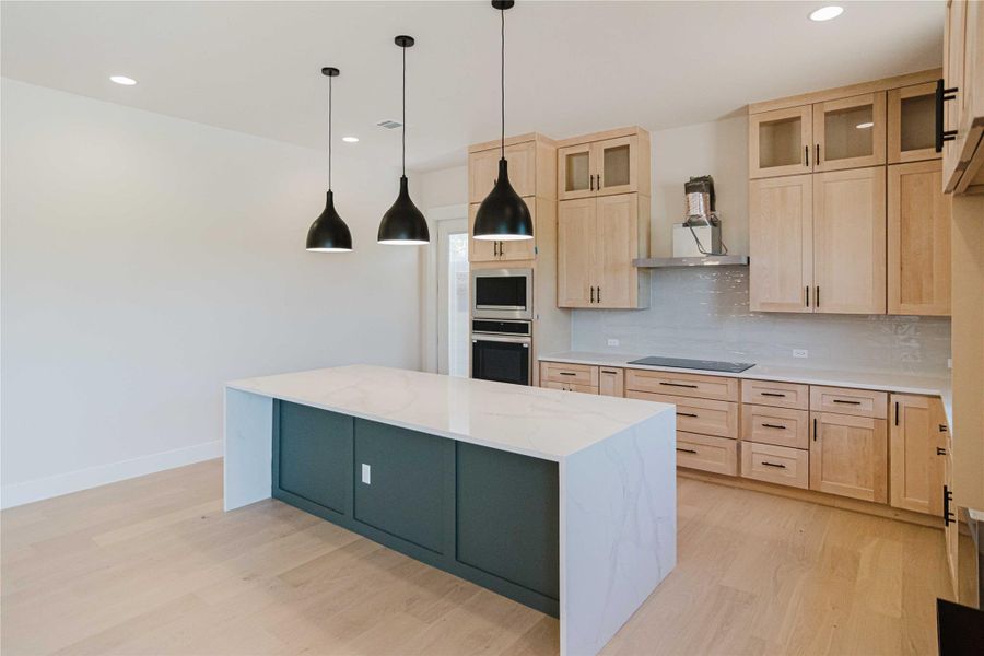 Kitchen featuring light brown cabinets, light stone countertops, hanging light fixtures, light wood-type flooring, and recessed lighting