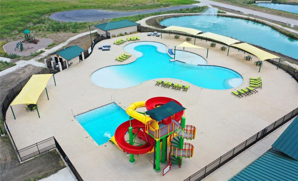 Expansive community pool area featuring a freeform main pool with a zero-entry section, an additional rectangular pool, and a colorful waterslide structure