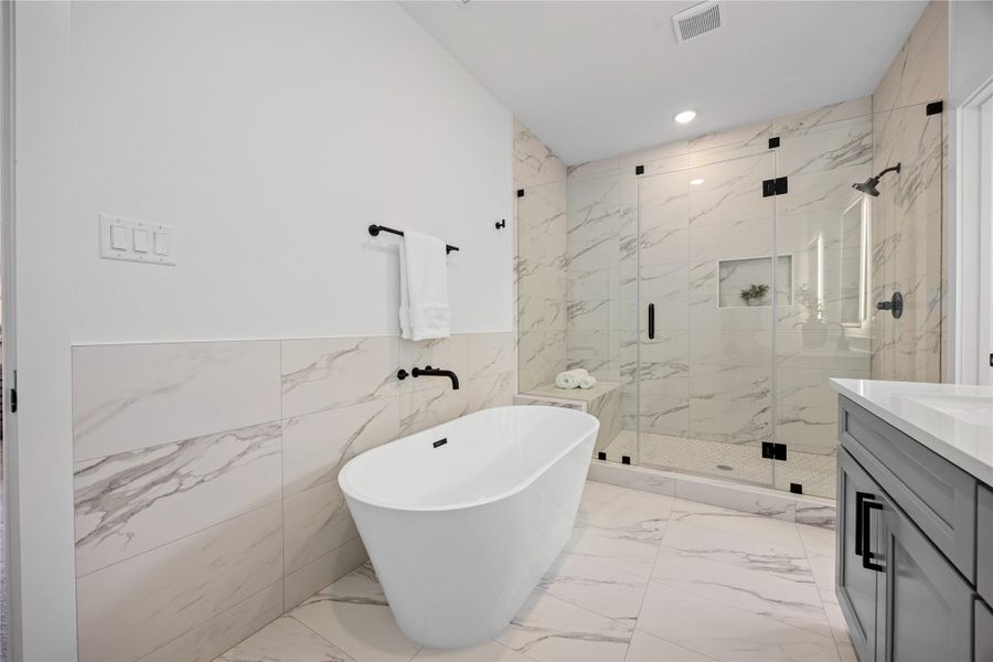 Another view of this stunning primary bathroom showcases the relaxing garden tub and walk-in shower with seat and elegant tile surround, soaring ceilings, and custom paint for a refined touch. Another view of this stunning primary bathroom showcases the relaxing garden tub and walk-in shower with seat and elegant tile surround, soaring ceilings, and custom paint for a refined touch.