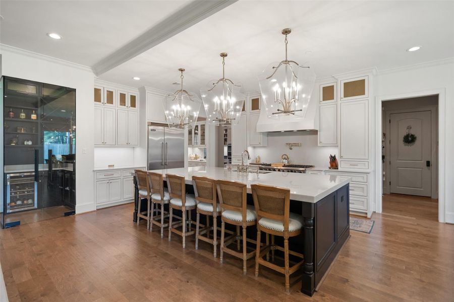 Expansive island kitchen showcasing quartzite countertops, a large center island, and abundant storage, complete with a Viking gas range, Viking refrigerator, pot filler