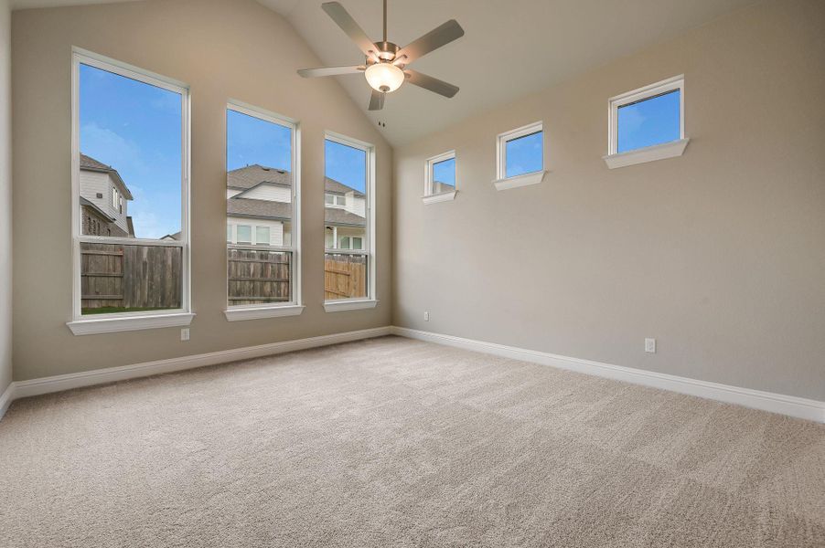 Carpeted empty room with lofted ceiling and ceiling fan