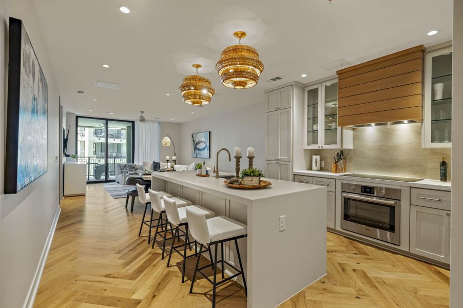 An inviting open-concept kitchen features a spacious island and herringbone wood floors.