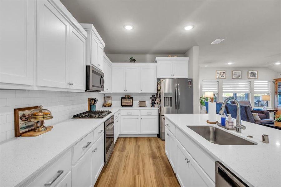 Kitchen with sink, white cabinetry, stainless steel appliances, and light hardwood / wood-style flooring