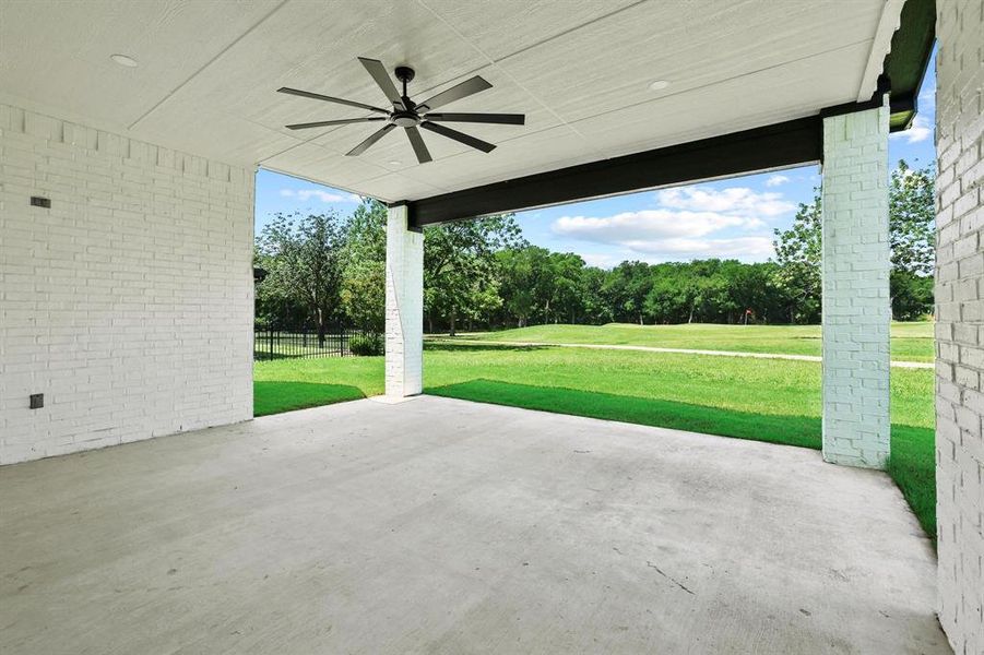 Covered patio featuring a concrete slab, white painted brick walls, exposed wood beam, and a ceiling fan Covered patio featuring a concrete slab, white painted brick walls, exposed wood beam, and a ceiling fan