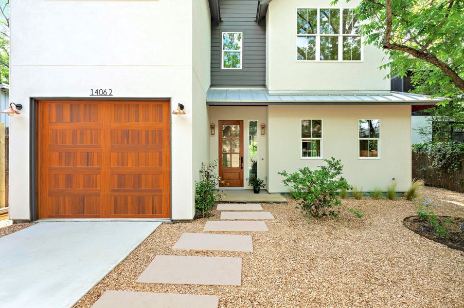 View of front of property featuring a standing seam roof, stucco siding, driveway, and metal roof