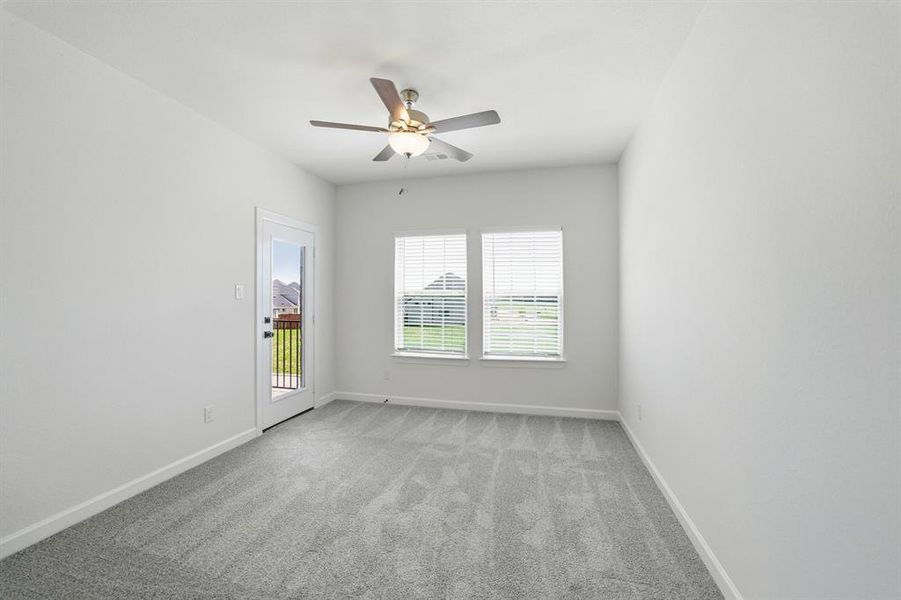 Bright room featuring light gray carpeting, a ceiling fan with integrated lighting, two windows with blinds, and a glass-paneled door
