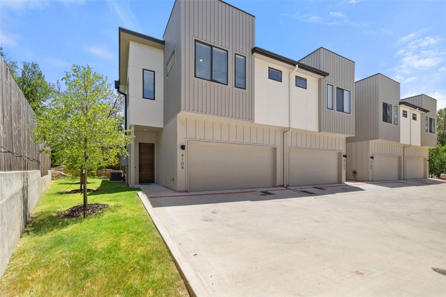 Contemporary home with an attached garage, concrete driveway, and a front yard Contemporary home with an attached garage, concrete driveway, and a front yard