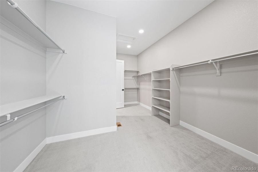 Expansive walk-in closet with custom storage and access to main level laundry room.