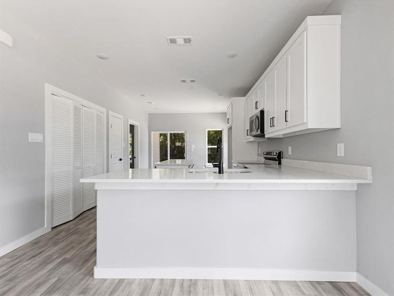Kitchen featuring stainless steel appliances, a sink, a peninsula, and light countertops