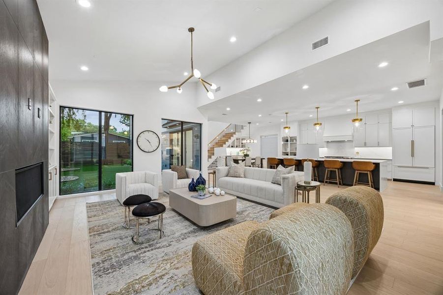 Light-filled living room with vaulted ceilings, statement fireplace wall, and expansive windows overlooking the backyard, all opening seamlessly to the kitchen for effortless entertaining. Light-filled living room with vaulted ceilings, statement fireplace wall, and expansive windows overlooking the backyard, all opening seamlessly to the kitchen for effortless entertaining.