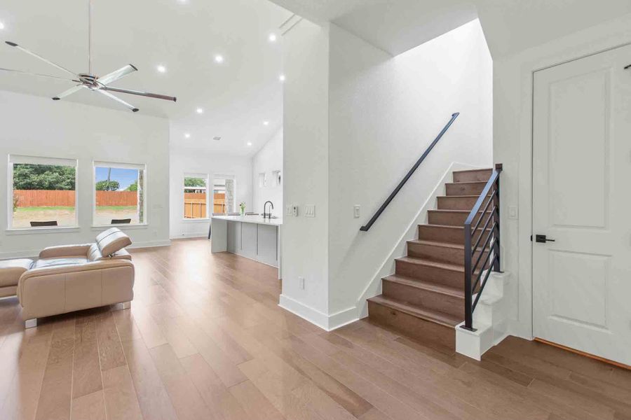 Wood-finish flooring throughout the main level featuring a modern staircase with dark metal railings