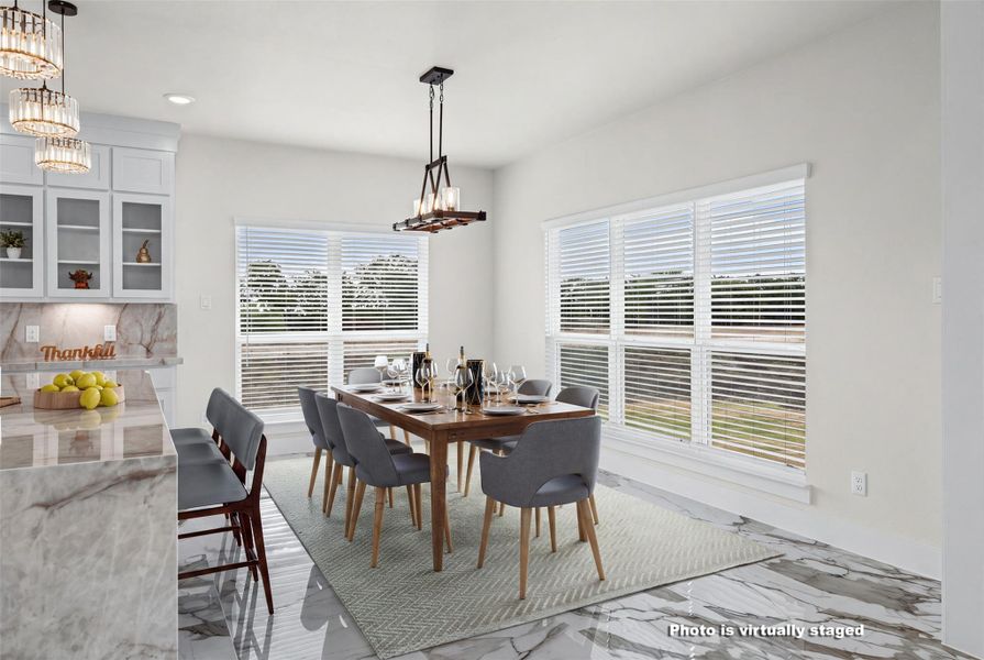 Polished tile flooring and large windows create a bright atmosphere in this dining area.
