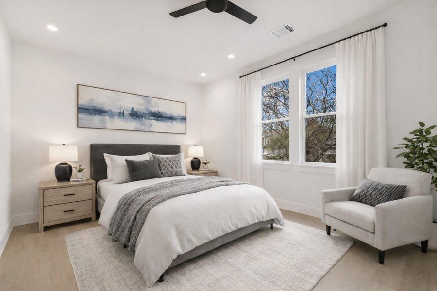 Staged photo-Light, bright, and ready for guests. The secondary bedroom features large windows that bring the outdoor greenery inside, highlighting the crisp white walls and flawless flooring.