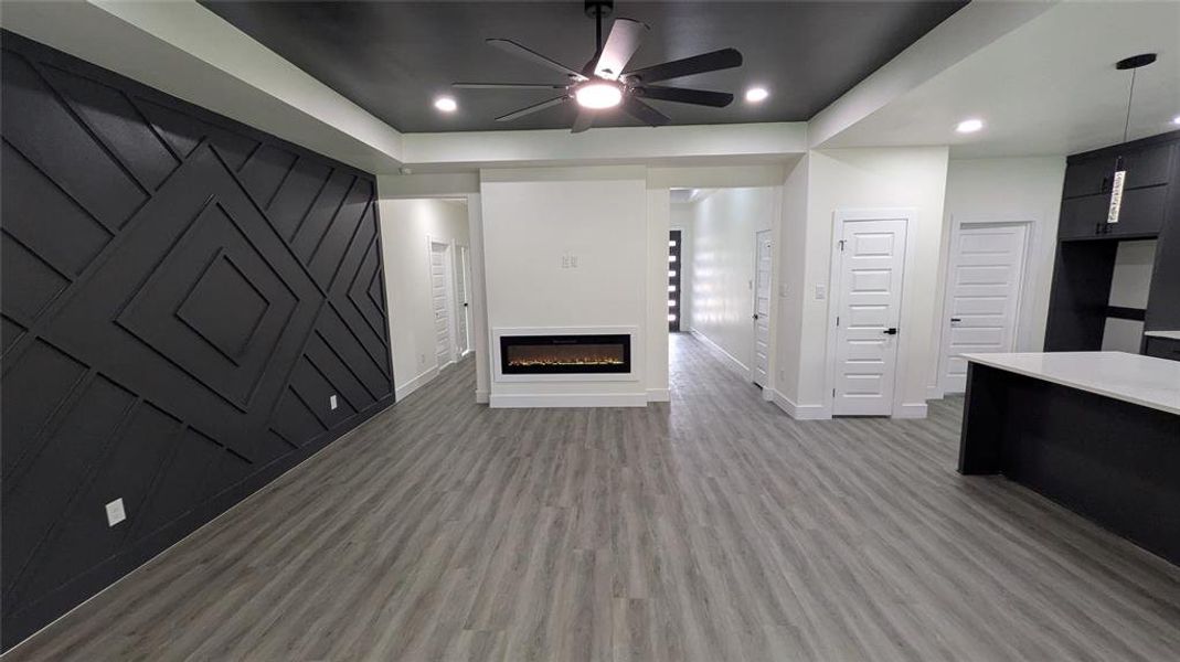 Unfurnished living room with a glass covered fireplace, a ceiling fan, baseboards, recessed lighting, and light wood-type flooring