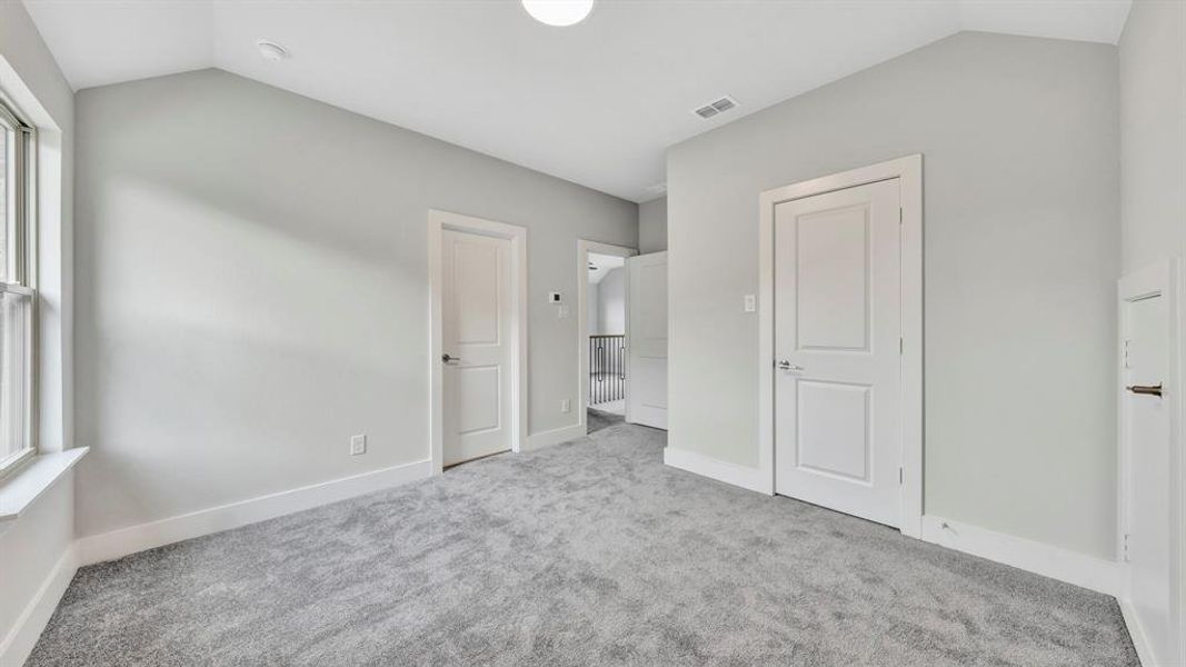 Unfurnished bedroom with lofted ceiling, light carpet, and multiple windows