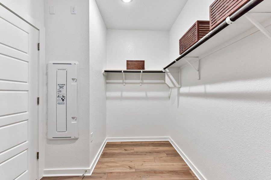 A spacious walk-in closet boasts generous built-in shelving and rich wood-inspired flooring. A spacious walk-in closet boasts generous built-in shelving and rich wood-inspired flooring.