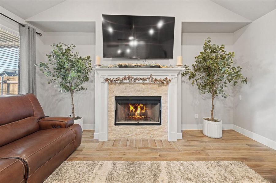 Living room featuring lofted ceiling, wood tiled floors, and a tile fireplace