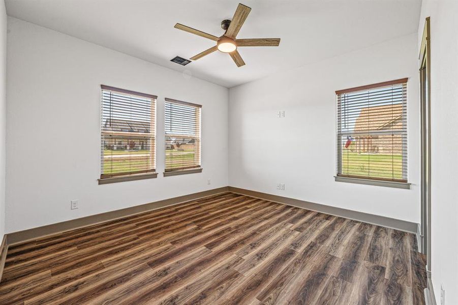 Empty room featuring dark wood-style flooring and a ceiling fan