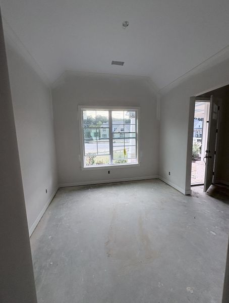 Crown molding accents the ceiling of this room featuring a multi-pane window and a neutral color palette