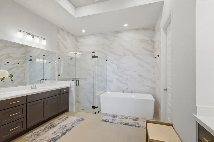 Upgraded primary bath features floor-to-ceilingtile, freestanding soaking tub, glass-enclosedshower and double vanity. Upgraded primary bath features floor-to-ceilingtile, freestanding soaking tub, glass-enclosedshower and double vanity.
