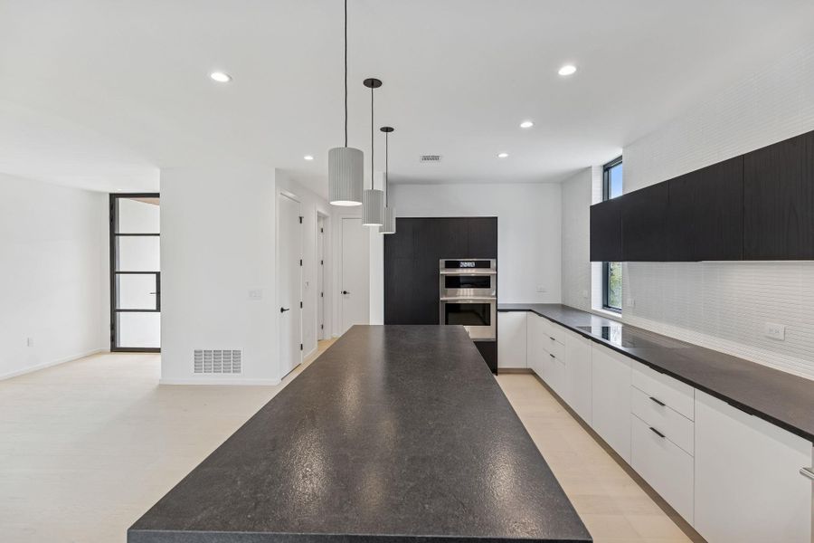 Kitchen with modern cabinets, pendant lighting, recessed lighting, decorative backsplash, and stainless steel double oven