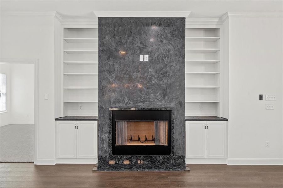 Detailed view of a fireplace, built in features, wood finished floors, and ornamental molding Detailed view of a fireplace, built in features, wood finished floors, and ornamental molding