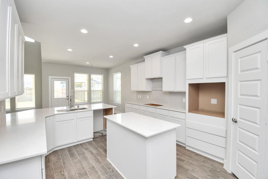 Culinary haven, featuring granite countertops, a tile backsplash, stainless steel appliances (to be installed), and 42” upper cabinets. Sample photo of completed home with similar floor plan. Actual colors and selections may vary.