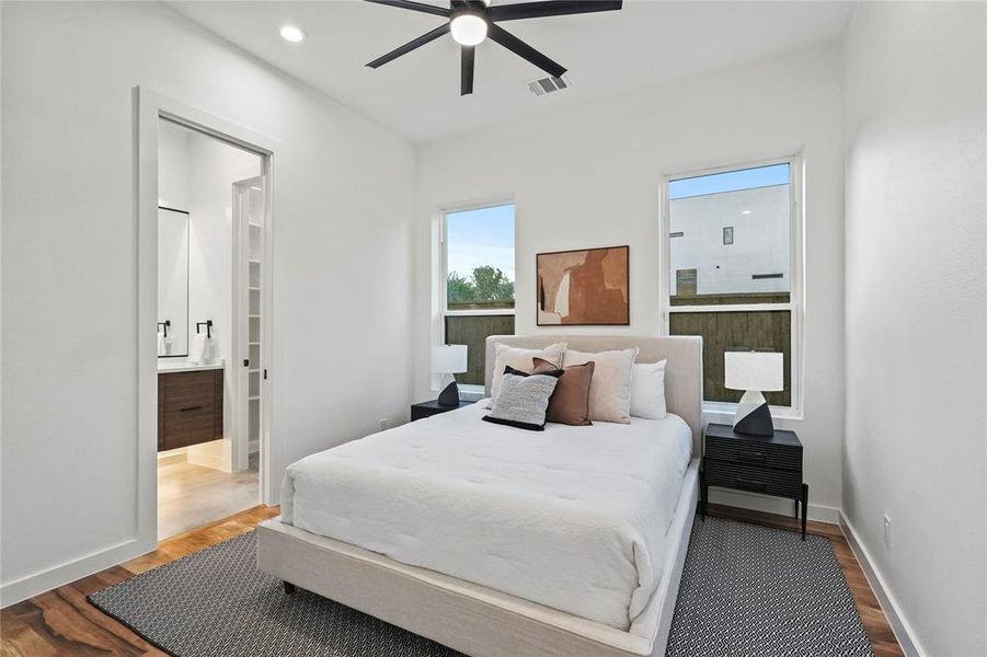 Bedroom with hardwood / wood-style floors, ceiling fan, and ensuite bath