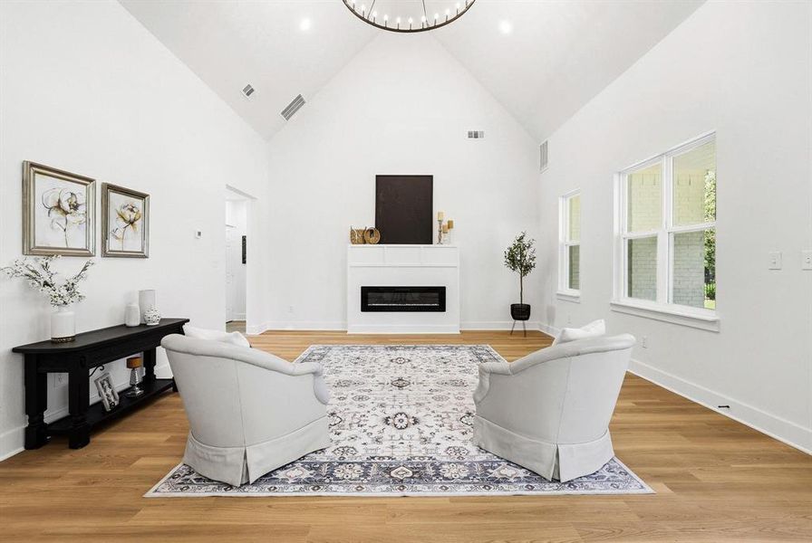 Vaulted ceiling great room featuring a contemporary linear fireplace, wood-finish flooring, and multiple large windows Vaulted ceiling great room featuring a contemporary linear fireplace, wood-finish flooring, and multiple large windows