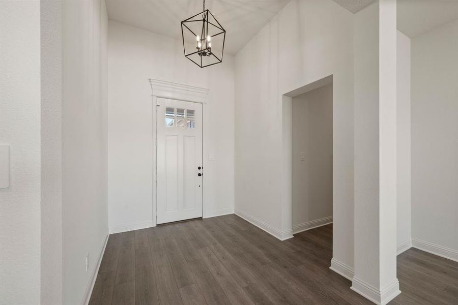 Foyer entrance with baseboards, a chandelier, and dark wood-style flooring