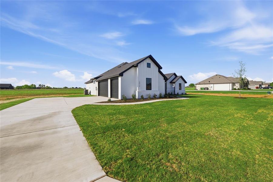 View of side of property with a lawn, concrete driveway, and a garage View of side of property with a lawn, concrete driveway, and a garage