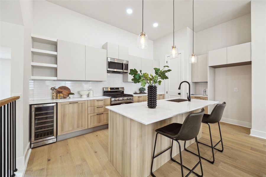 Modern kitchen featuring sleek cabinetry, a spacious island with seating, stainless steel appliances, and elegant pendant lighting. Perfect for entertaining and culinary creativity.