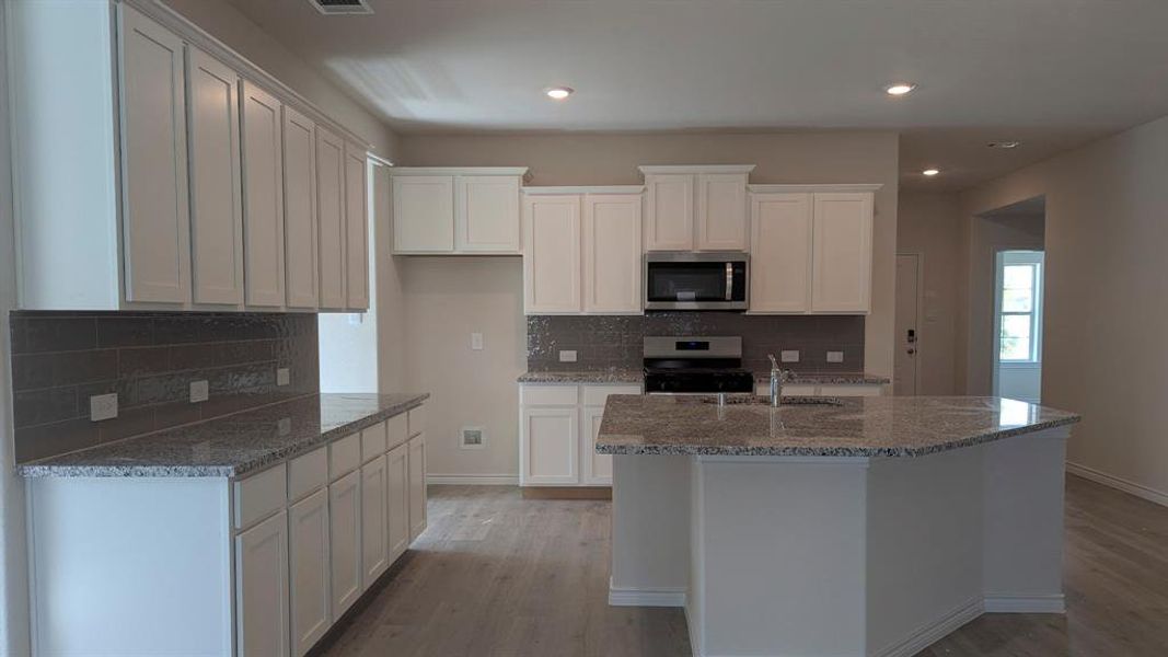 Kitchen with appliances with stainless steel finishes, recessed lighting, white cabinetry, and light wood-style flooring Kitchen with appliances with stainless steel finishes, recessed lighting, white cabinetry, and light wood-style flooring