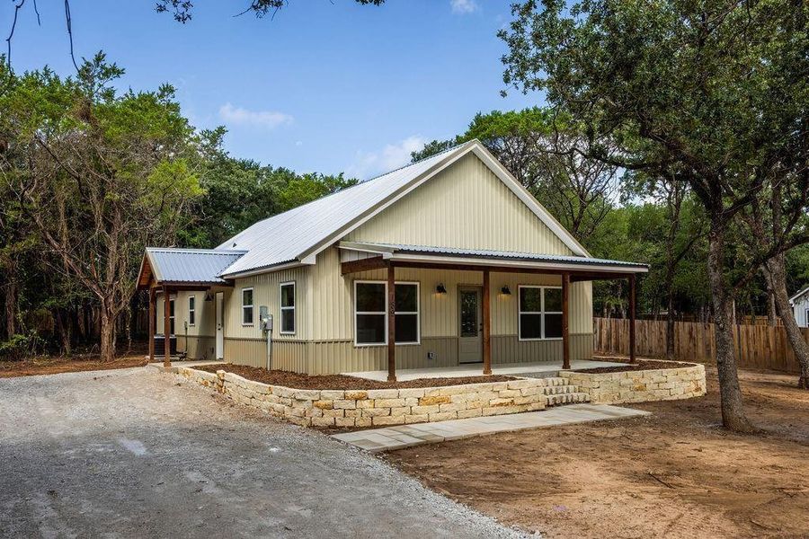 View of front of property featuring covered porch, a metal roof, and driveway