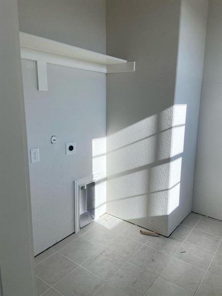 Dedicated laundry area featuring a built-in shelf, tiled flooring, and all necessary utility connections