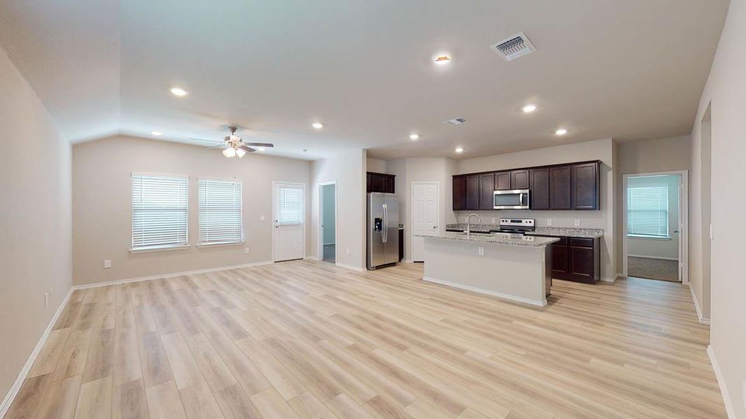 An open concept living area boasts generous light-toned flooring, leading to a modern kitchen with ample counter space. An open concept living area boasts generous light-toned flooring, leading to a modern kitchen with ample counter space.