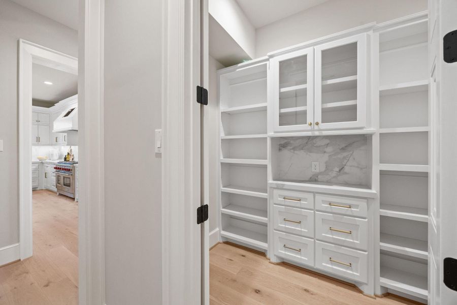 A spacious walk-in pantry offers custom site built shelving, drawers & cabinets w/ additional counter space for appliances.