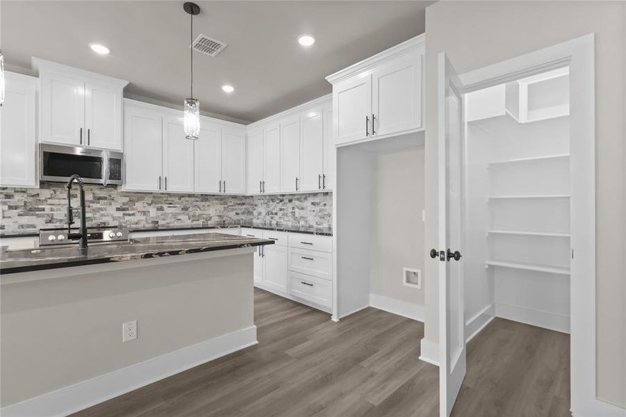 Kitchen featuring dark hardwood / wood-style floors, pendant lighting, and white cabinets