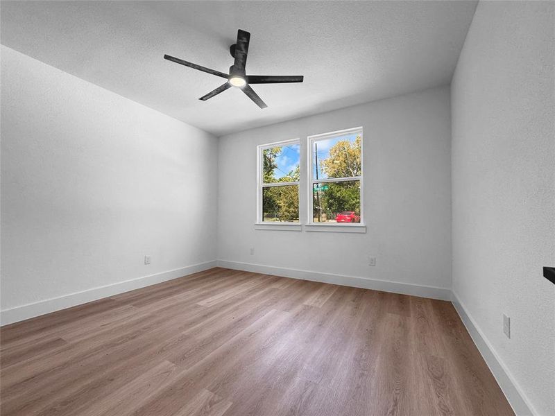 Empty room featuring light wood finished floors, a textured ceiling, and ceiling fan