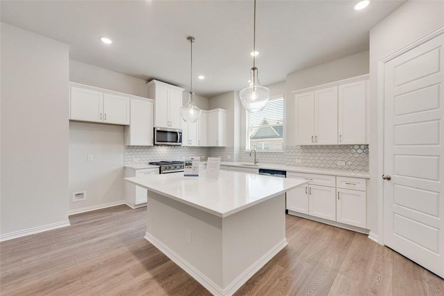 Kitchen featuring appliances with stainless steel finishes, light wood-type flooring, white cabinetry, and a center island