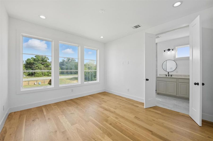 Unfurnished bedroom with light wood-style floors, recessed lighting, and ensuite bath Unfurnished bedroom with light wood-style floors, recessed lighting, and ensuite bath
