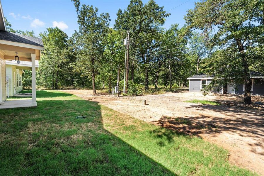 Expansive outdoor area featuring a partially grassed lawn and mature trees Expansive outdoor area featuring a partially grassed lawn and mature trees