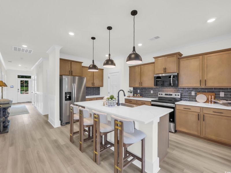 Kitchen with brown cabinets, appliances with stainless steel finishes, backsplash, a breakfast bar area, and recessed lighting