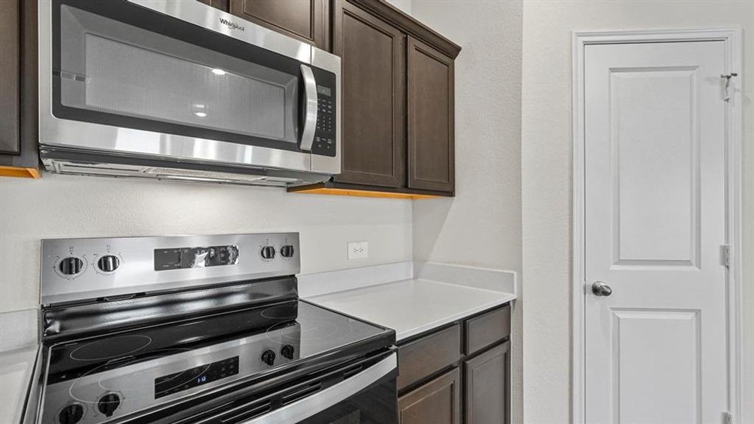 Kitchen featuring stainless steel appliances, dark wood finish cabinetry, and a textured wall